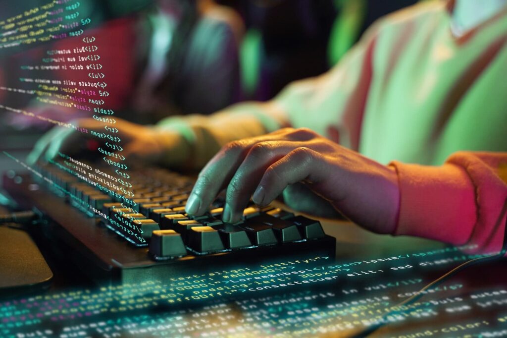 A person's hand on a computer keyboard next to the program code