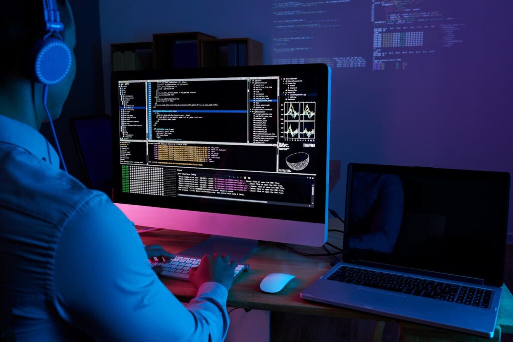 IT specialist checking code at computer in the dark office at night