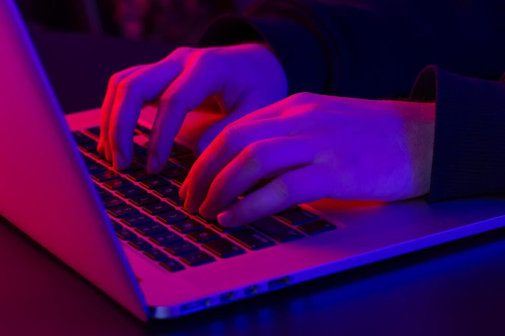 Man using laptop close up under neon lighting