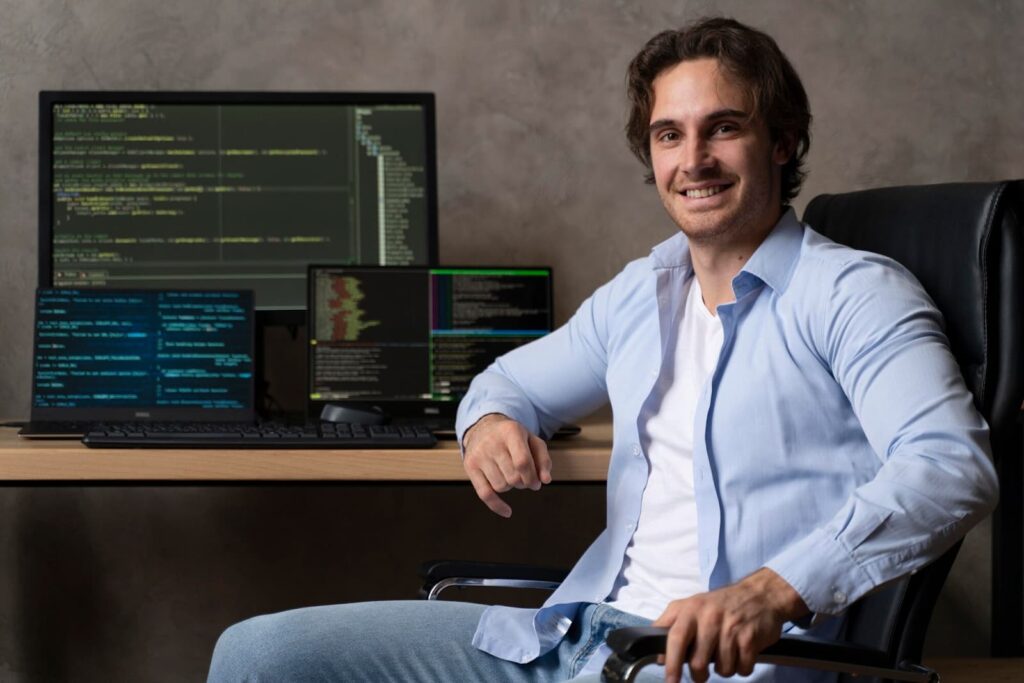 A man sits in front of a computer with codes